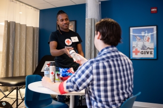 An American Red Cross volunteer giving supplies to a person in a hospital